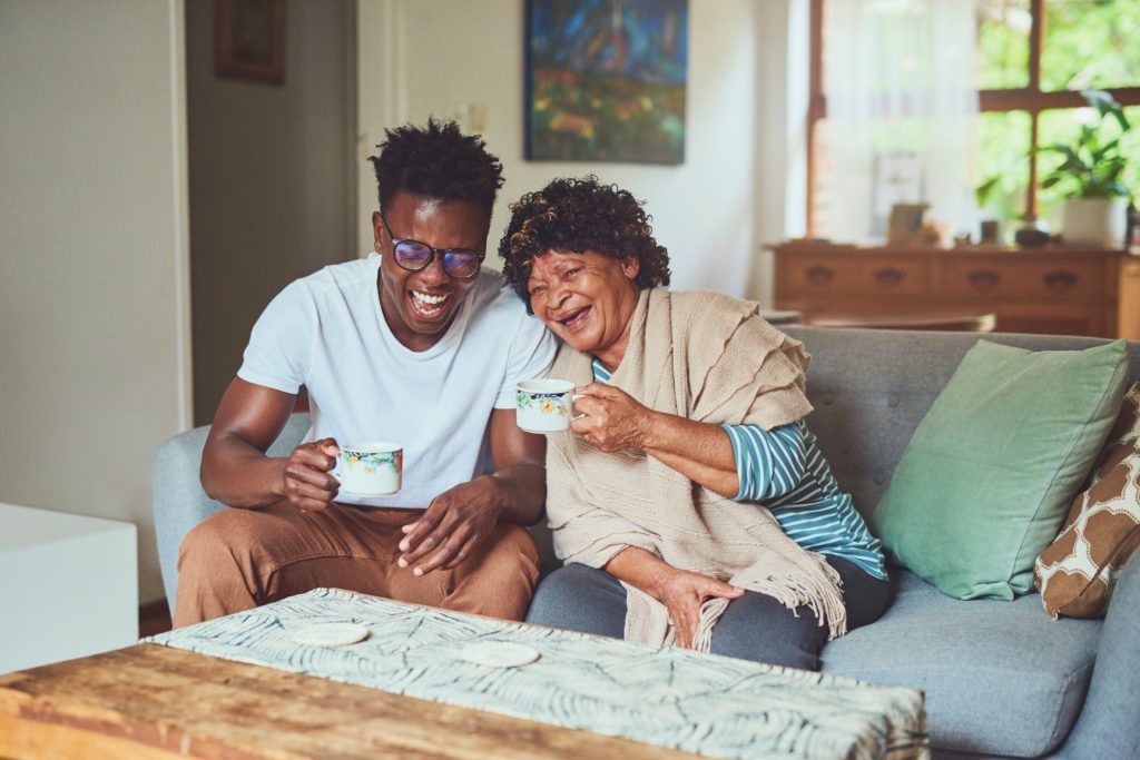Image of a man and an older woman laughing on the couch