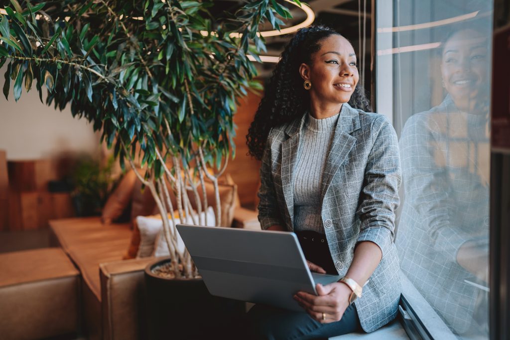 Smiling woman working on a laptop—exploring home care franchise ownership